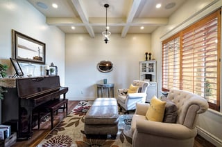 Elegant custom home living room with upright piano, tufted chairs, and bright natural lighting.