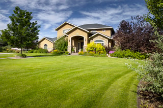 Beautiful custom home with manicured lawn, curved walkway, and colorful flowering garden beds.