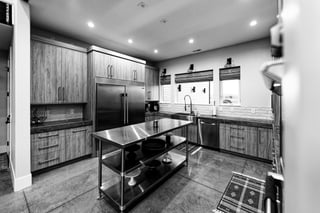 Modern custom home kitchen with stainless steel appliances, wood cabinetry, and sleek black and white design.