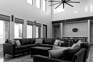 Modern custom home living room with tall windows, sectional sofa, and open double-height ceiling.