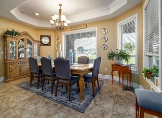 Elegant custom home dining room with carved wood table, china cabinet, and natural sunlight.
