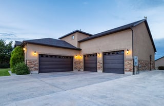 Custom home with three car garage and stone stucco exterior at dusk.
