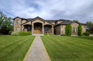 Elegant two story custom home with stone accents, central walkway, and manicured front lawn.