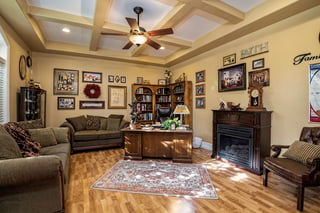 Cozy custom home office with wooden desk, built-in bookcase, fireplace, and family décor accents.